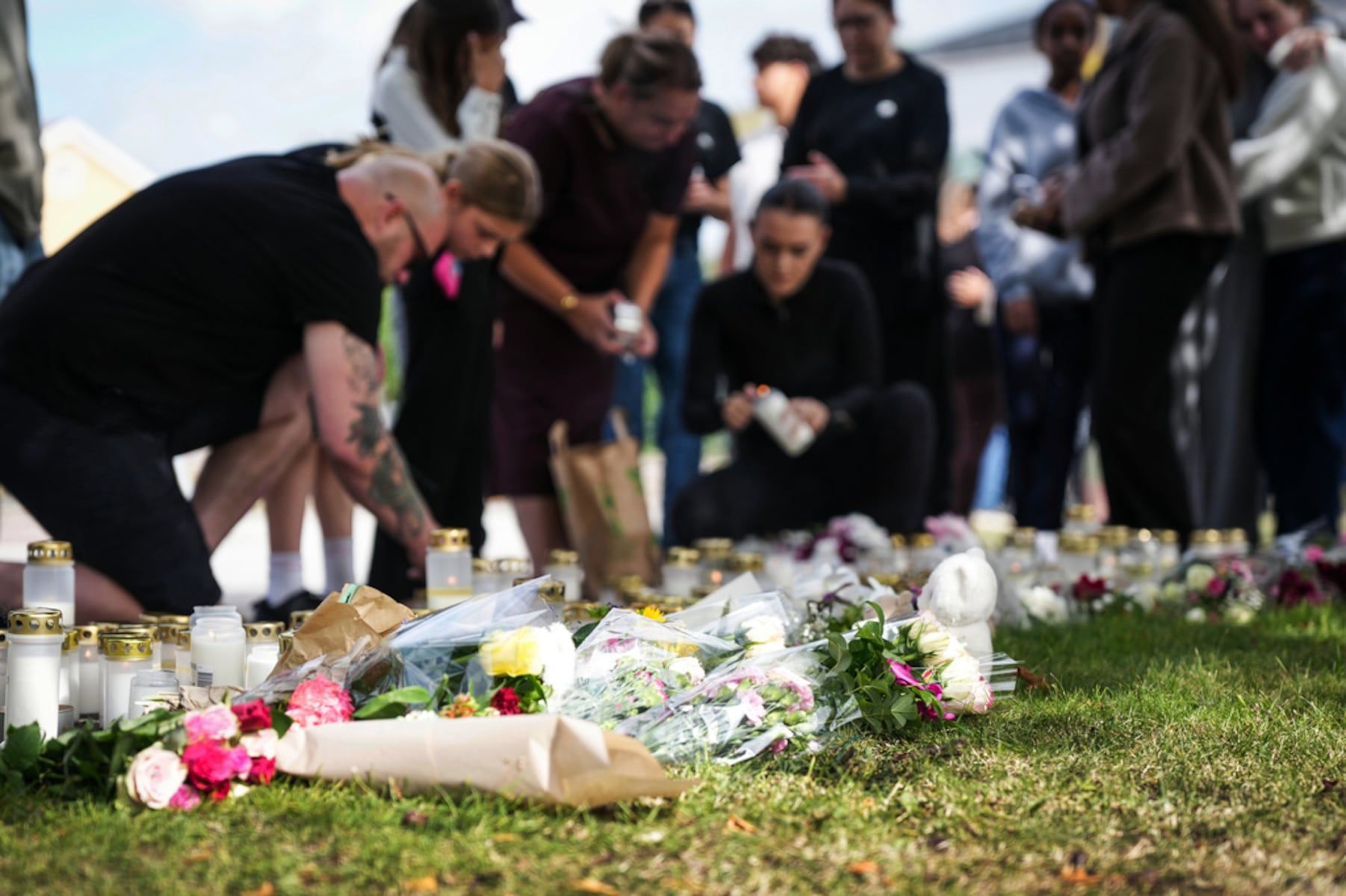 People leave flowers and candles at a makeshift memorial outside a school in Fagersta, Sweden, the day after the attack. - Magnus Lejhall/TT via AP