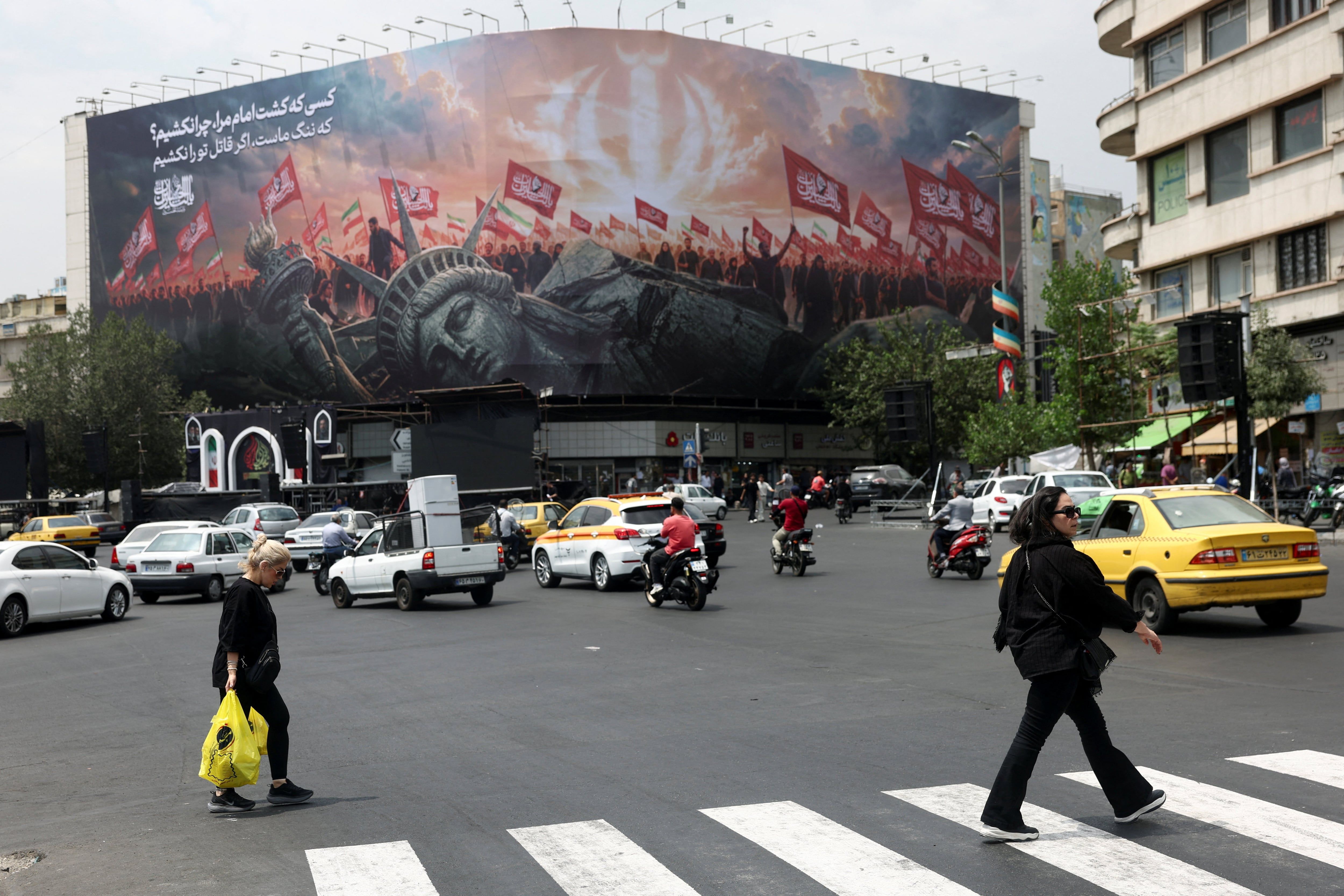 People walk past an anti-U.S. billboard on a street in Tehran, Iran, August 3, 2026. - Majid Asgaripour/WANA via Reuters