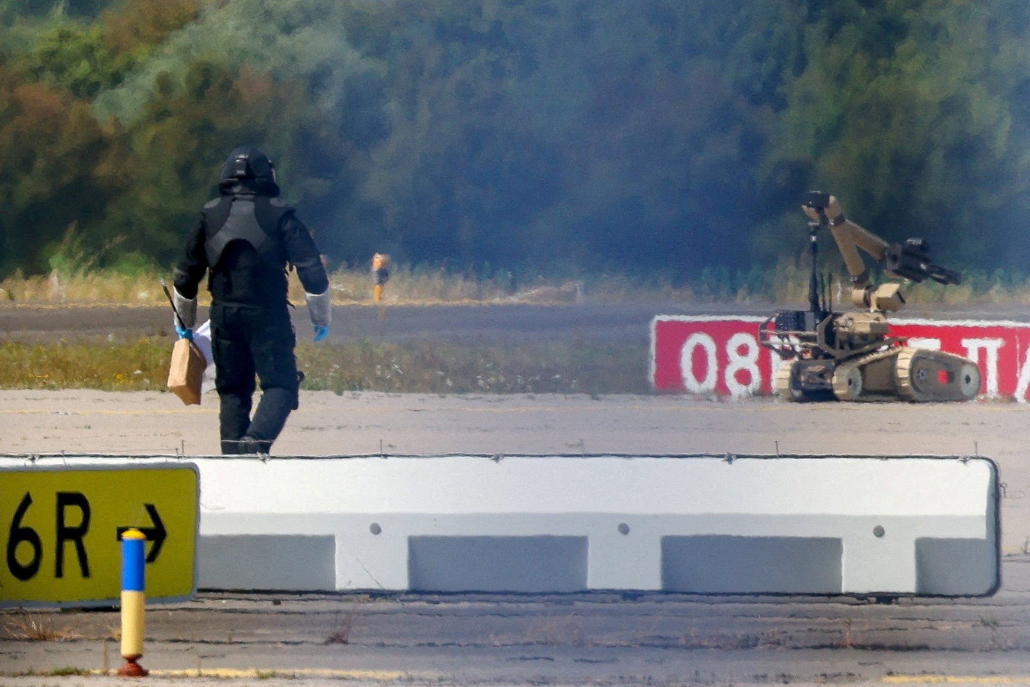 A police officer in protective clothing walks next to an explosive-disarming robot at Leipzig/Halle Airport after explosives experts examined a drone found near a runway. - Reuters/Axel Schmidt