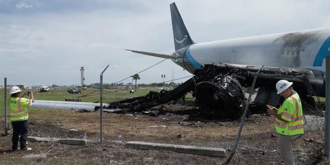 National Transportation Safety Board investigators inspect the site where an Amazon Prime Air cargo plane overran a runway at Miami International Airport. - NTSB handout via Reuters